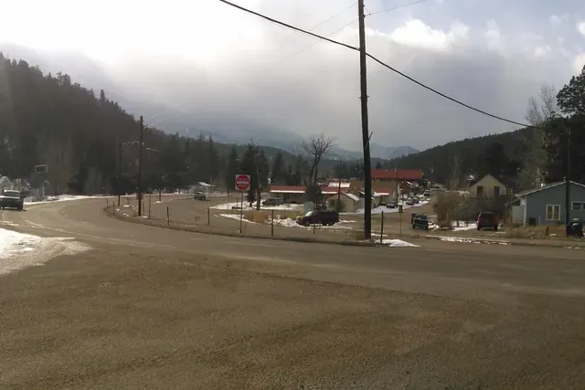US 285 curving through downtown Bailey with buildings and forested mountains