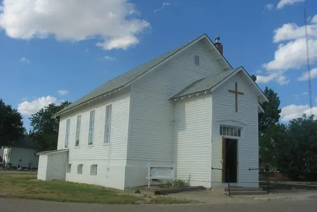 A white frame church in Briggsdale under a summer sky