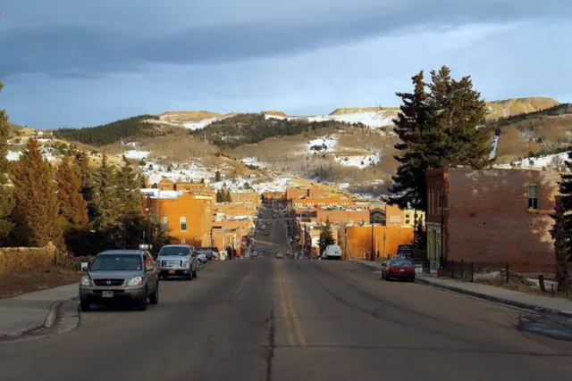 A Cripple Creek street of brick buildings with snow-dusted hills behind