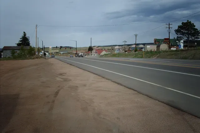 US 24 running past homes and buildings at Divide under a stormy sky