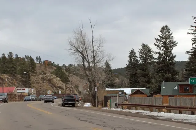 Highway 74 through Kittredge with pines, cottonwoods and log buildings along Bear Creek