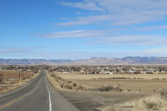 Highway leading into Loma past irrigated fields with mesas in the distance