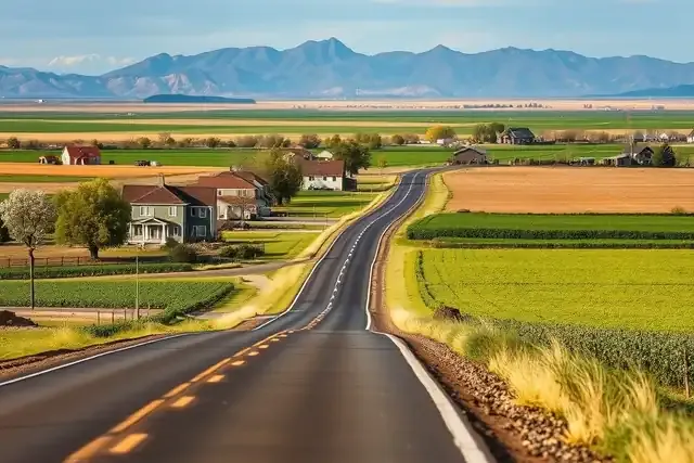 Rural homes along a two-lane highway with green fields and cottonwoods on the northern Colorado plains