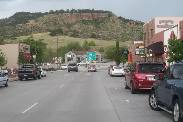Older sandstone and wood houses near the river with red cliffs behind in Lyons