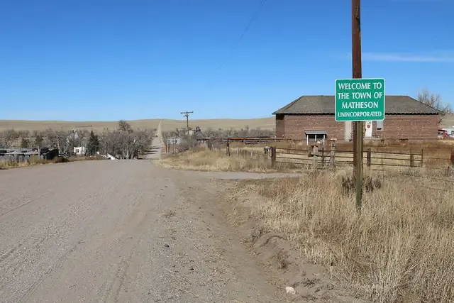 A gravel road leading into Matheson past a brick building on the open plains