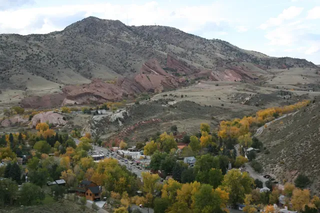 Small older stone and wood houses beneath red sandstone rocks in Morrison