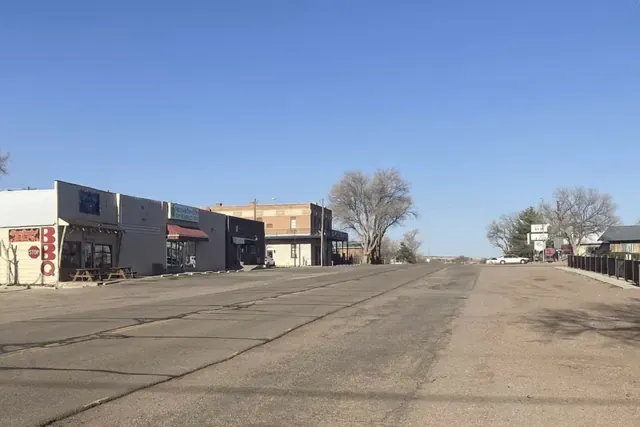 Wide main road through Penrose with low buildings and bare trees on a clear day