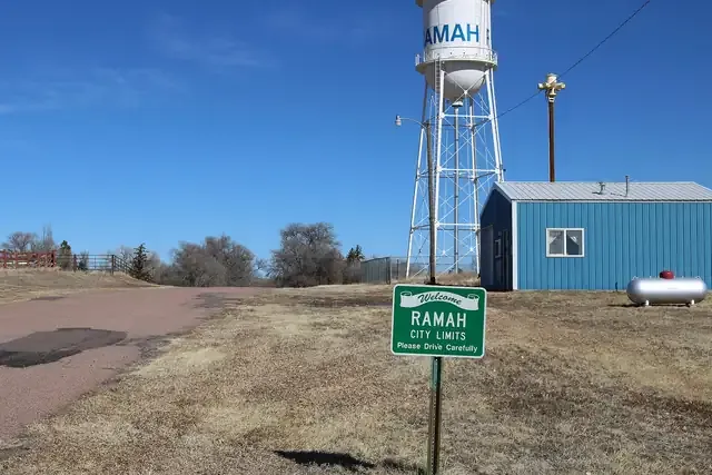 Ramah's town water tower and a small building on the open prairie under a blue sky