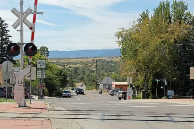 Highway 67 through Sedalia with a railroad crossing, cottonwoods and foothills in the distance
